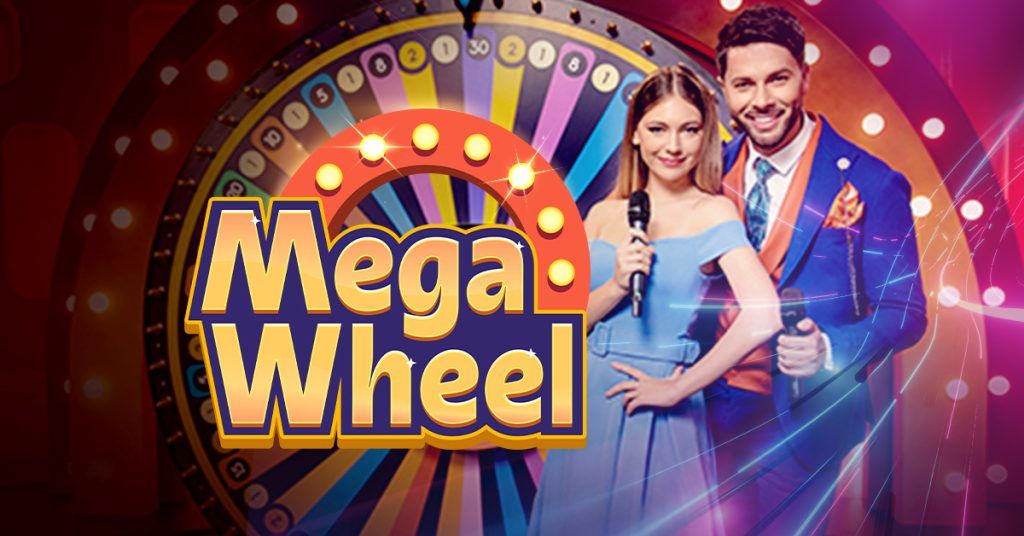 Dua host berdiri di depan roda besar permainan Mega Wheel dengan lampu warna-warni, simbol dari permainan kasino interaktif populer.